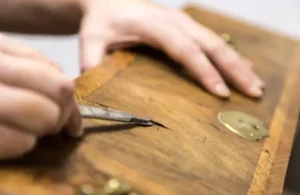 Team member repairing veneer on antique console drawer
