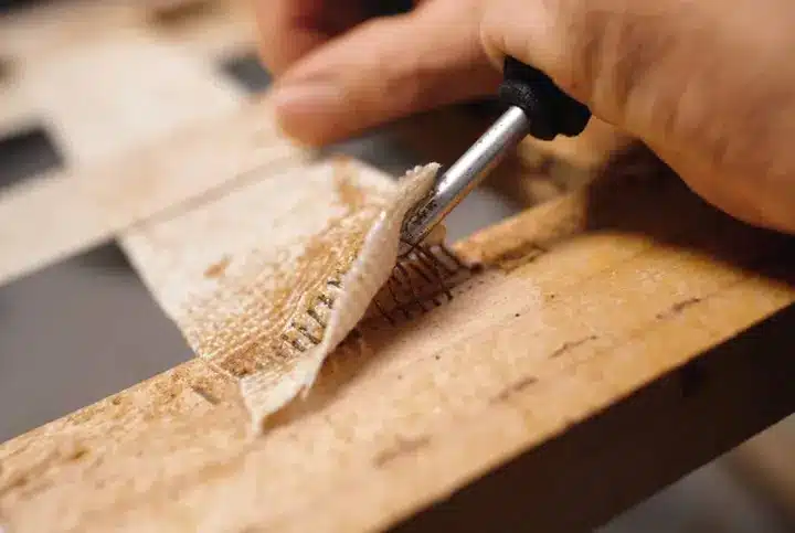 Upholsterer removing old material from an antique chair as part of the refurbishing and restoration process.