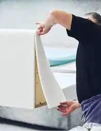 Technician stapling fabric to custom headboard frame